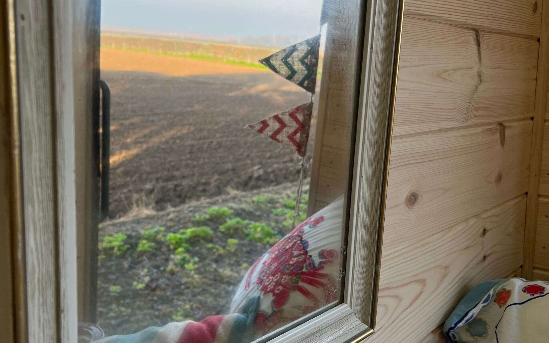 Rustic farm trailer window overlooking Norfolk farmland at Barn Drift.