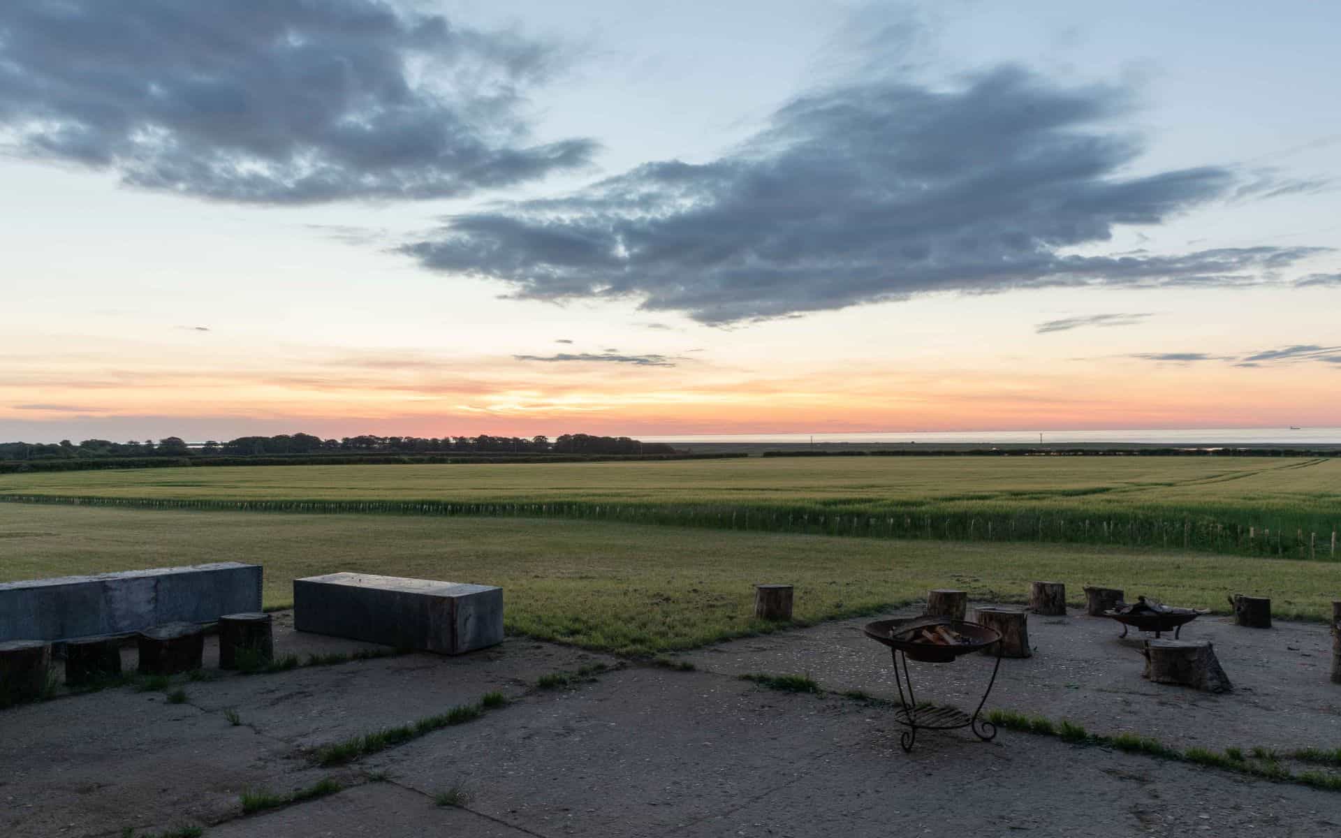 Sunset over Norfolk fields with outdoor seating, capturing rural tranquility.