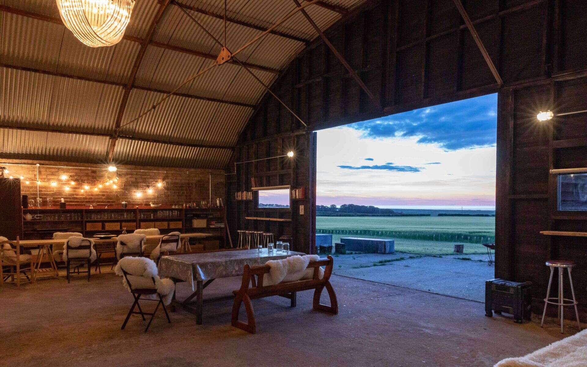 Rustic barn interior with sunset view over Norfolk countryside, perfect for events.