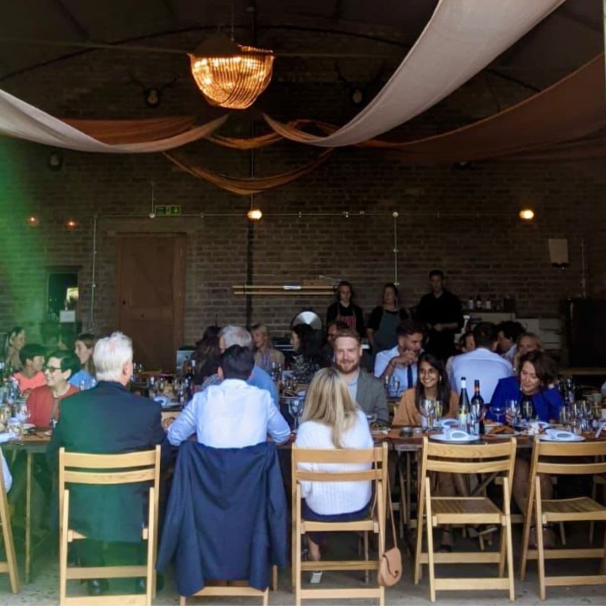 Enjoying a warm gathering at The Hanger, Barn Drift Norfolk, with guests dining in a rustic, charmin.