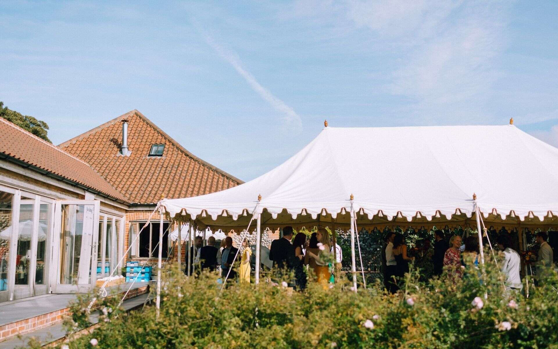 A lush outdoor wedding setup under a large white marquee in Norfolk.