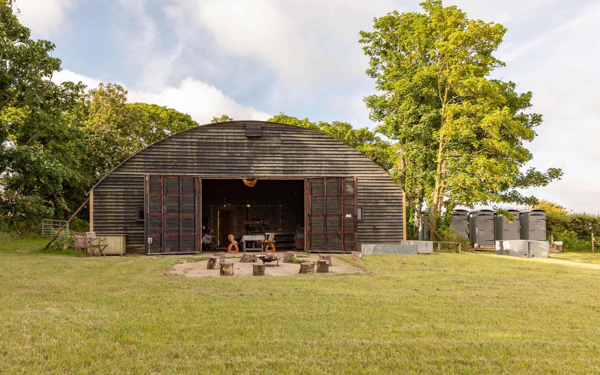 Rustic barn venue surrounded by lush greenery for woodland wedding celebrations in Norfolk.